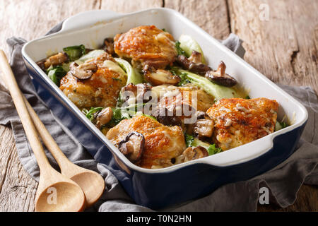 Homemade baked chicken thigh recipe with baby bok choy, shiitake mushrooms and cheese sauce in a rustic style closeup on the table. horizontal Stock Photo
