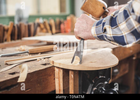 Instrument maker using tools to carve a mandolin Stock Photo
