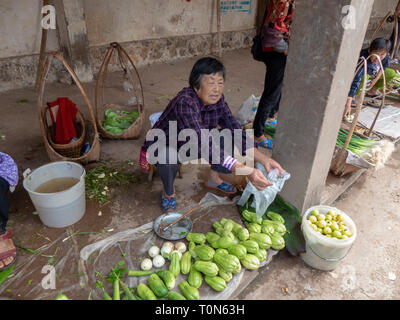 Vendor sells a small selection of fruit and vegetables in the food market of Jianshui, Honghe prefecture, Yunnan province, China. Stock Photo