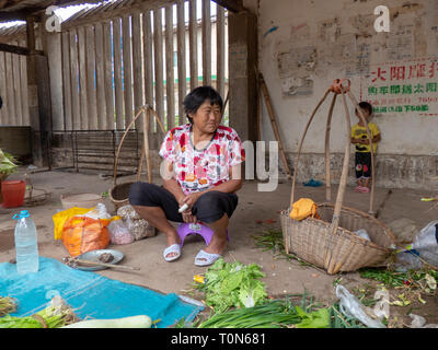 Vendor sells a small selection of fruit and vegetables in the food market of Jianshui, Honghe prefecture, Yunnan province, China. Stock Photo