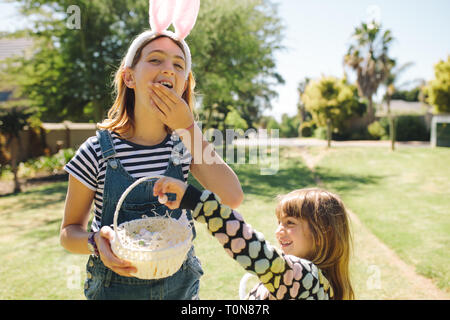 Kids eating sweets from a basket standing in a garden. Kids having fun playing in a garden on a sunny day. Stock Photo