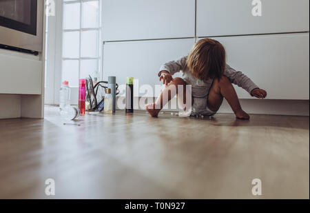 kid playing at home with household articles. Kid playing alone at home sitting on the floor. Stock Photo