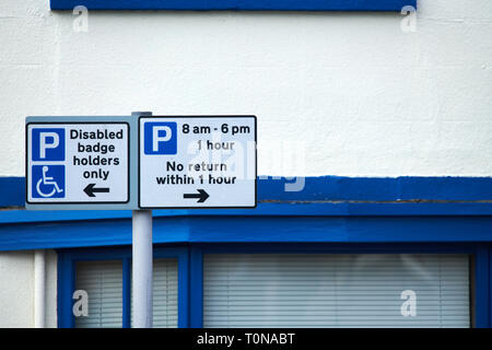 Notices showing parking places for disabled badge holders and parking places with a time limit of one hour. Stock Photo