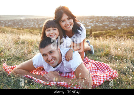 Family smiling lying on the grass on the nature. Stock Photo