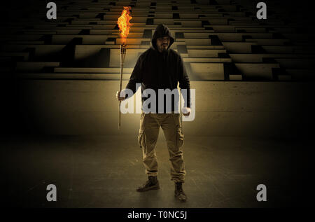 Ugly, aberrant man coming out from the labyrinth with burning flambeau on his hand  Stock Photo