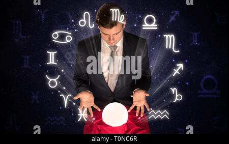 Young handsome astronaut looking for inspiration in his crystal magic ball  Stock Photo