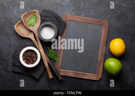 Cooking wooden utensils, condiments and spices on stone kitchen table. Food cooking template concept. Top view with blackboard for your text. Flat lay Stock Photo