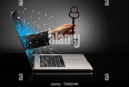 Hand with huge vintage key coming out of a laptop with sparkling effects  Stock Photo