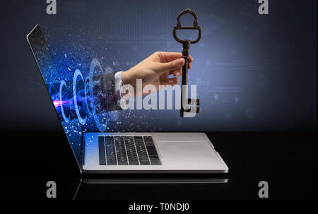 Hand with huge vintage key coming out of a laptop with sparkling effects  Stock Photo