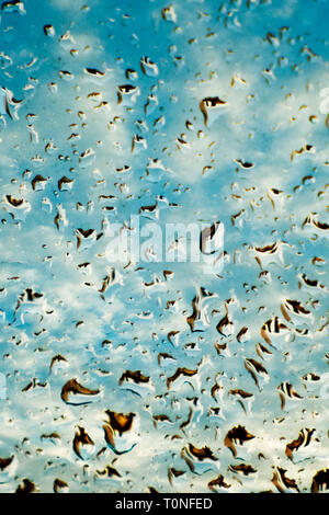 blue sky behind a window covered with rain drops Stock Photo
