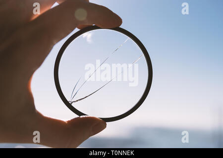 Hand hold broken photo-filter over blue sky background. Stock Photo