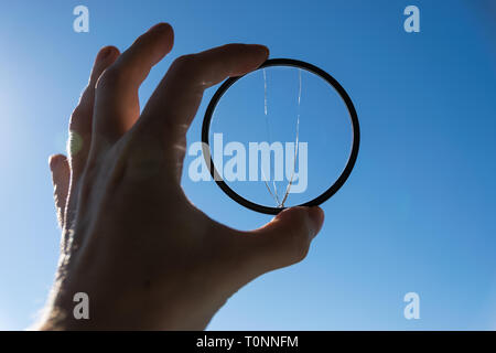 Hand hold broken photo-filter over blue sky background. Stock Photo