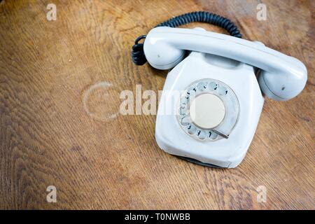 Old white cable telephone on old table surface. Communication technology from 80s - concept Stock Photo