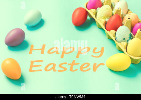 Bright Easter eggs lie in a box on a blue background Stock Photo