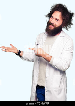 Crazy scientist with funny long hair amazed and smiling to the camera while presenting with hand and pointing with finger. Stock Photo