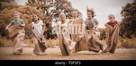 Children having a sack race in park Stock Photo