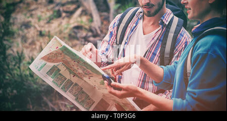 Couple discussing over map in forest Stock Photo
