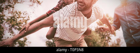 Happy grandfather looking at man giving piggy backing to son Stock Photo