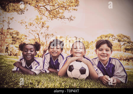 children soccer team smiling at camera while lying on the grass Stock Photo