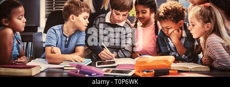 Teacher helping schoolgirl with her homework in classroom Stock Photo