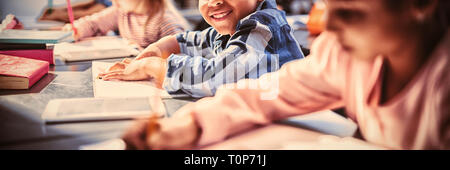 Portrait of smiling schoolboy doing his homework in classroom Stock Photo