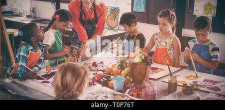 Teacher assisting schoolkids in drawing class Stock Photo