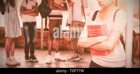 School friends bullying a sad girl in corridor Stock Photo