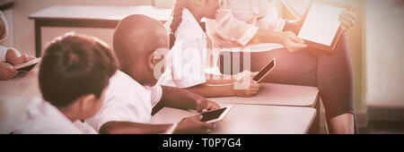 Teacher teaching kids on digital tablet Stock Photo