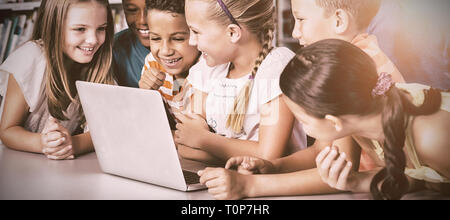 School kids using laptop in library Stock Photo