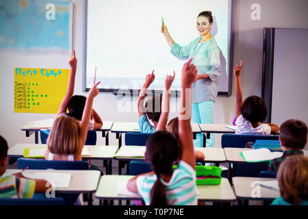 Teacher teaching students using projector in classroom Stock Photo