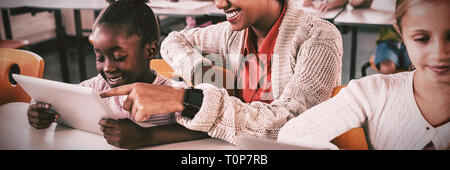Teacher helping student with tablet computer Stock Photo