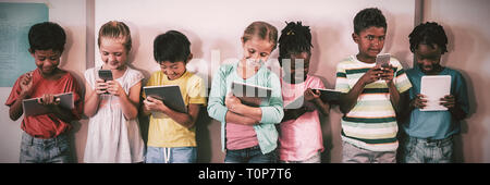 Happy pupils standing with technology Stock Photo