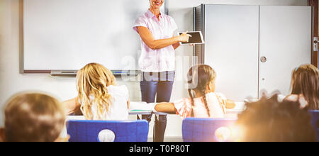 Teacher teaching kids on digital tablet Stock Photo