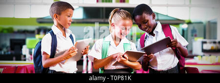 School kids using digital tablet in school cafeteria Stock Photo