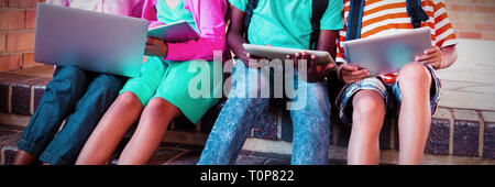 Kids sitting on staircase using laptop and digital tablet Stock Photo