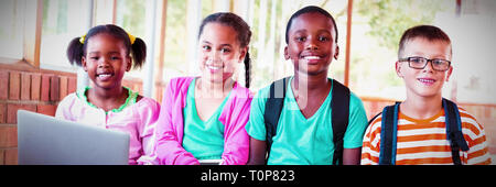 Portrait of kids using a laptop and digital tablet on stairs Stock Photo