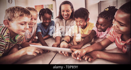 Smiling students and teacher using a tablet computer Stock Photo