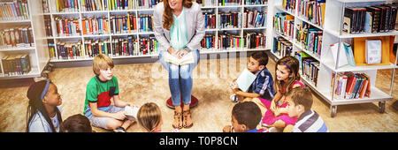 Teacher reading books to her students Stock Photo