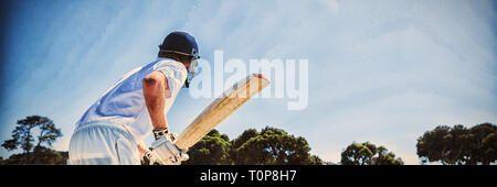 Side view of cricket player batting while playing on field Stock Photo