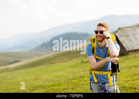 View of happy young handsome red hair man hiking in the countryside Stock Photo