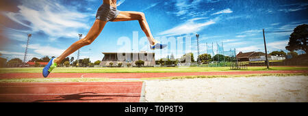 Female athlete performing a long jump Stock Photo