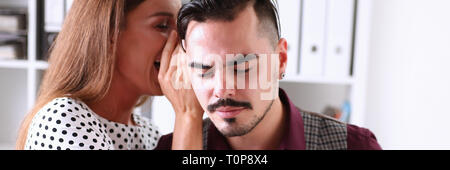 Woman gossip whispers in the ear of news to a man Stock Photo