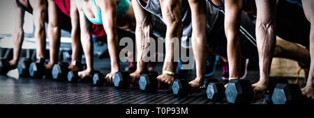 People doing push ups with dumbbell in gym Stock Photo