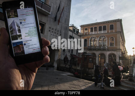 Venice, Italy. 21st Mar, 2019. The discounts for the weekend made by Palazzo Bauer, that is in the background, are shown on a smartphone on 21 March 2019, in Venice Italy. Hotels in Venice, especially from 3 stars to 4, are making big discounts for the weekends because of the AirBnb apartment in the city, and because of the new hotels and hostels in the inland city, Mestre and especially in Via Piave in front of the railway station, 15 minutes far from Venice by bus or by train. Credit: Simone Padovani/Awakening/Ģ����ý Live News Stock Photo