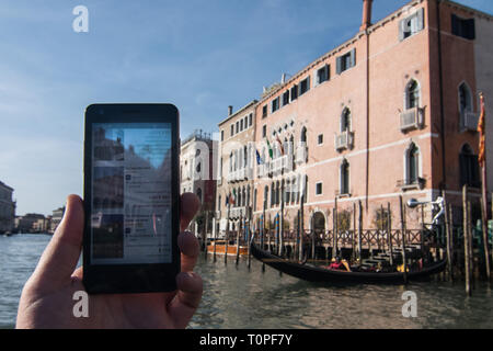 Venice, Italy. 21st Mar, 2019. The discounts for the weekend made by Hotel Ca' Sagredo, that is in the background, are shown on a smartphone on 21 March 2019, in Venice Italy. Hotels in Venice, especially from 3 stars to 4, are making big discounts for the weekends because of the AirBnb apartment in the city, and because of the new hotels and hostels in the inland city, Mestre and especially in Via Piave in front of the railway station, 15 minutes far from Venice by bus or by train. Credit: Simone Padovani/Awakening/Ģ����ý Live News Stock Photo