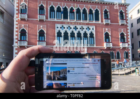 Venice, Italy. 21st Mar, 2019. The discounts for the weekend made by Hotel Danieli, that is in the background, are shown on a smartphone on 21 March 2019, in Venice Italy. Hotels in Venice, especially from 3 stars to 4, are making big discounts for the weekends because of the AirBnb apartment in the city, and because of the new hotels and hostels in the inland city, Mestre and especially in Via Piave in front of the railway station, 15 minutes far from Venice by bus or by train. Credit: Simone Padovani/Awakening/Ģ����ý Live News Stock Photo