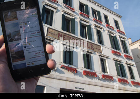 Venice, Italy. 21st Mar, 2019. The discounts for the weekend made by Hotel Metropole, that is in the background, are shown on a smartphone on 21 March 2019, in Venice Italy. Hotels in Venice, especially from 3 stars to 4, are making big discounts for the weekends because of the AirBnb apartment in the city, and because of the new hotels and hostels in the inland city, Mestre and especially in Via Piave in front of the railway station, 15 minutes far from Venice by bus or by train. Credit: Simone Padovani/Awakening/Ģ����ý Live News Stock Photo