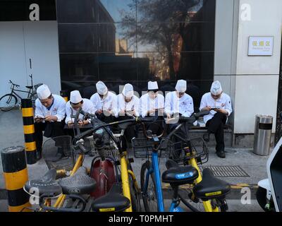 Beijing, China. 12th Mar, 2019. Chefs look at their phones during a break in Beijing, capital of China, March 12, 2019. Credit: Lan Hongguang/Xinhua/Alamy Live News Stock Photo