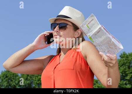 young lady holding map and using smarphone in summer Stock Photo