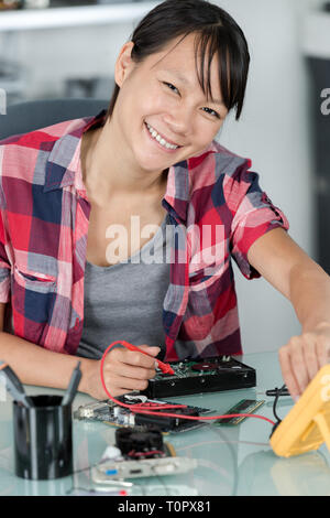 female asian computer technician using multimeter Stock Photo
